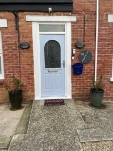 a white door on a brick house with two plants at The Rosefield in Weymouth