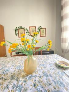 um vaso cheio de flores amarelas sentado numa mesa em Euploia Apartment em Ischia