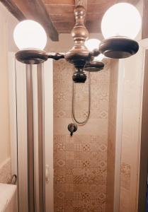 un ventilatore a soffitto con 2 luci accese in bagno di Casa Melograno a SantʼAndrea di Compito