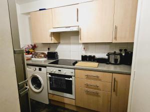 a kitchen with a stove and a washing machine at Lovely Fully Furnished One Bed Flat To Let in Enfield Lock