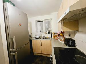 a small kitchen with a refrigerator and a sink at Lovely Fully Furnished One Bed Flat To Let in Enfield Lock