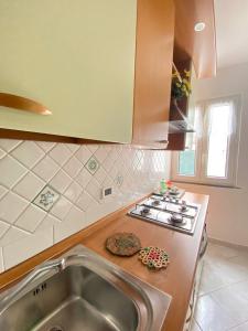 uma cozinha com um lavatório e um fogão forno superior em Euploia Apartment em Ischia
