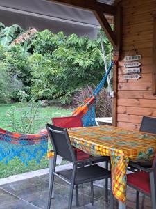 a table and chairs on a porch with a hammock at Villa Cachiman in Pointe-Noire