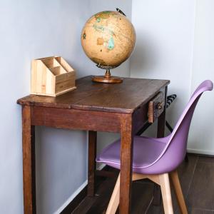 un bureau en bois avec un globe et une chaise violette dans l'établissement Casa Bruna Luxury Lofts, à Tampico