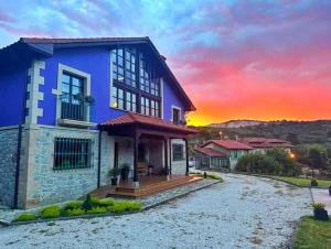 a blue house with a sunset in the background at Refugio del Cares in Ortiguero