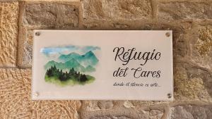 un cartel en una pared con una montaña y árboles en Refugio del Cares en Ortiguero