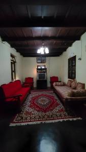 a living room with red couches and a rug at Heritage Homestay in Chikmagalūr