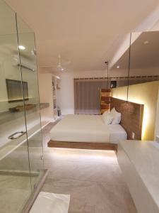 1 dormitorio con cama blanca y pared de cristal en Kuun Taak Tulum en Tulum