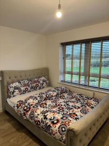 a bedroom with a bed with a floral comforter at A stunning 3 bed luxury holiday home in Buckinghamshire