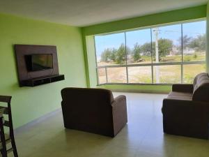 a living room with two couches and a large window at Residencial Veleiros Do Mar in Capão da Canoa