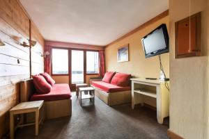 une chambre d'hôtel avec deux chaises rouges et une télévision dans l'établissement Résidence L'Ours Blanc - maeva Home - Appartement 3 pièces 7 personnes - Sélection MAE-8949, à Huez