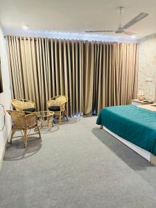een slaapkamer met een bed, stoelen en gordijnen bij Zayn villa in Mount Lavinia