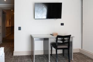 a desk with a chair and a television on a wall at Hotel José Nogueira in Punta Arenas