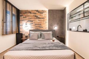 a bedroom with a large bed with a brick wall at Almasi Luxury Suites Marquise in Alexandroupoli