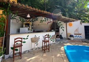 a kitchen with stools and a counter next to a pool at Pousada Alto da Praia in Arraial d'Ajuda