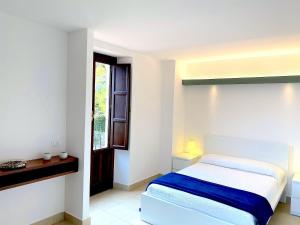 a white bedroom with a bed and a window at Archè Apartment in Taormina