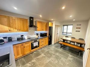 a kitchen with wooden cabinets and a table in it at Smiddy Cottage Bauds in Buckie