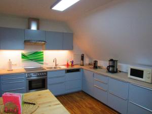 eine Küche mit blauen Schränken, einem Waschbecken und einem Tisch in der Unterkunft Charming apartment in Haren Ems 