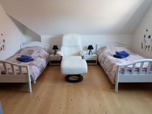 1 Schlafzimmer mit 2 Betten, einem weißen Stuhl und einem Stuhl in der Unterkunft Cosy apartment in Porta Westfalica in Porta Westfalica