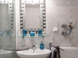 een badkamer met een wastafel, een bad en een spiegel bij Holiday apartment Leo by the lake in Bad Wiessee