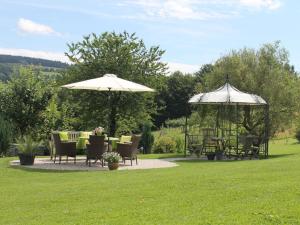 deux parasols, tables et chaises dans une cour dans l'établissement Nice apartment in Gersfeld, à Gersfeld