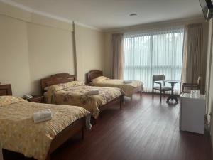 Habitación de hotel con 3 camas y mesa en Hotel Oblitas en Cochabamba