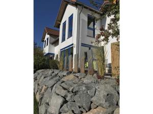 a white house with blue windows and a stone wall at Nice apartment in Daun-Waldkönigen 