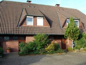 een huis met een bruin dak en een boom bij Holiday home Kleiner Friese Dangast in Varel
