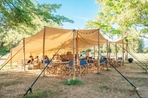 Tienda con mesas y sillas en un campo en Lodg'ing Nature Camp Anjou NEW 2024, en Sainte-Gemme-sur-Loire