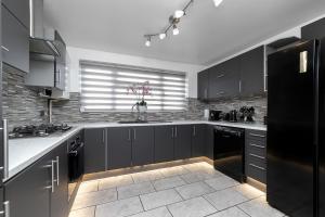 a kitchen with black cabinets and a black refrigerator at Contractors Dream~POOL TABLE~Close to Luton Airport~Three Double Bedrooms in Luton
