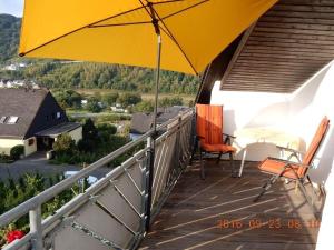 an umbrella and chairs on a balcony with a view at Holiday apartment Moselle Panorama in Enkirch