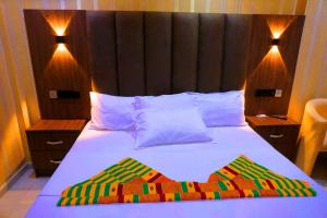 a bedroom with a bed with a wooden headboard at Texas Royal Hotel in Pokuase +18 photos