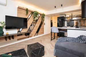 a living room with a large television and a staircase at Almasi Luxury Suites Marquise in Alexandroupoli