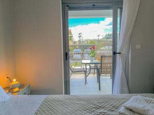a bedroom with a bed and a view of a balcony at Newly Built House Steps from the Beach: Everything Within Walking Distance - Enjoy a Car-Free Stay in Agia Marina Nea Kydonias
