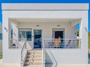 a white house with stairs and a balcony at Newly Built House Steps from the Beach: Everything Within Walking Distance - Enjoy a Car-Free Stay in Agia Marina Nea Kydonias