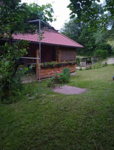 Cabaña de madera con techo rojo en un patio en Apartment Letić, en Šipovo