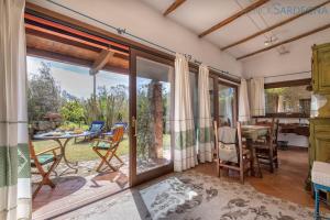 a living room with sliding glass doors and a table and chairs at Alghero Villa Rujia with garden and pool in Porto Conte