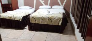 Dos camas en una habitación con mantas. en Hotel Santa Lucia - Oficial, en Piura
