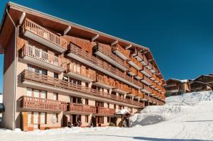 un gran edificio con nieve delante en Résidence Le Mont Soleil - maeva Home - Appartement 3 pièces 7 personnes Séle 17, en Mâcot La Plagne