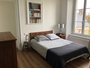 a bedroom with a bed and a book shelf at l'appart de la Maison du Hommeel in Gratot