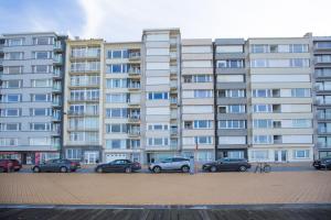 duży apartamentowiec z samochodami zaparkowanymi na parkingu w obiekcie Bright Apartment With Sea View w Ostendzie