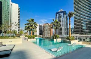 Elite LUX Holiday Homes - Elegant 2BR Suite in Business Bay Dubai في دبي: مسبح على كرسيين وعلى أفق المدينة