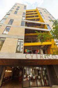 un edificio alto de color amarillo con un restaurante delante de él en Hotel Cytrico, en Medellín