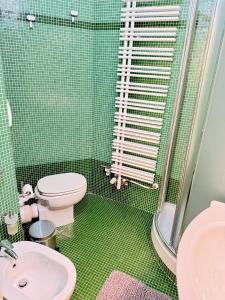 a green tiled bathroom with a toilet and a sink at San Filippo Studio Biella Centro in Biella +27 photos