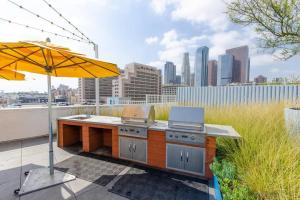 une terrasse avec une cuisine extérieure et un parasol dans l'établissement Cozy 2bed Condo with balcony & a rooftop pool, à Los Angeles