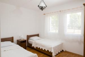 two beds in a white room with two windows at Krašograd in Pisarovina