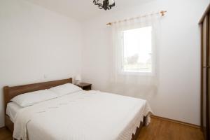 a white bedroom with a bed and a window at Krašograd in Pisarovina