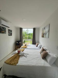 two large beds in a room with a window at Pousada Hércules Beach Paradise in Maragogi