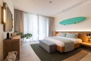 a bedroom with a bed with a surfboard on the wall at Silvestre Nosara Hotel & Residences in Nosara