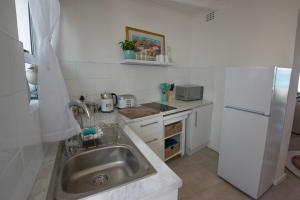 Una cocina con fregadero y refrigerador blanco. en Beach Haven, en Ciudad del Cabo